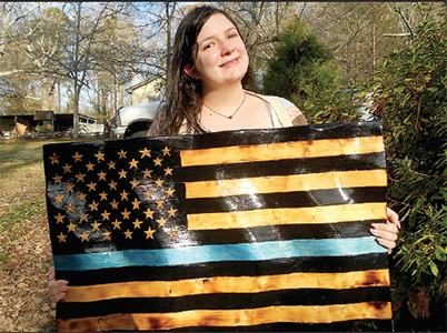 Erika, holds up a 'Back the Blue' American-style flag she made at their shop. 