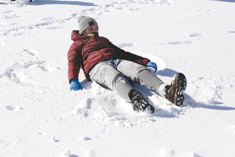 A student makes a snow angel 
