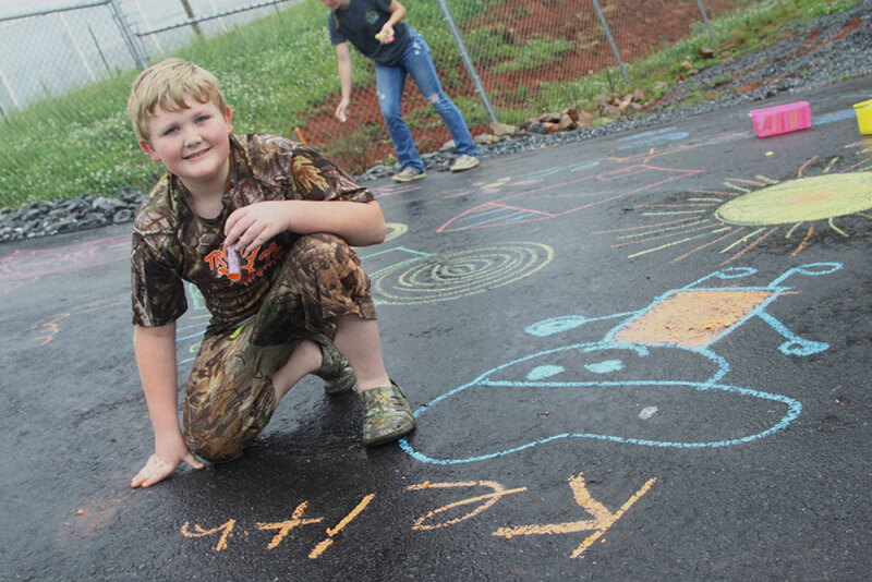 Keith Tessneer spells out his name in the chalk art area during the Burns High FFA Farm Day on Saturday, May 4th. 