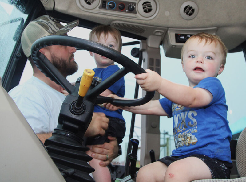 Houston Lattimore with twins Jace and Judd check out a tractor at the Burns High School Farm Day. 