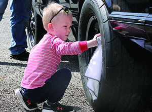 Braxton Bradley, age 4, cleans the wheels on his father's 1990 LX Mustang 