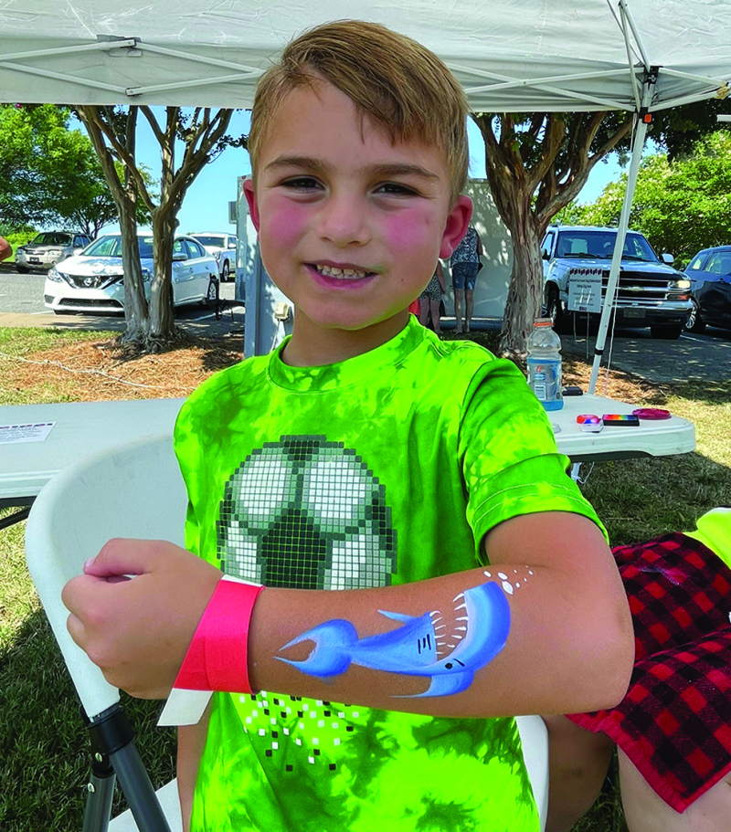 Wyatt Torres shows off a shark painted on his arm at the National Carrousel Day Celebration at the Shelby City Park on Saturday July 23rd.