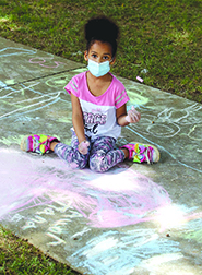 Tiana Accor colors the sidewalk during Chalk Fest