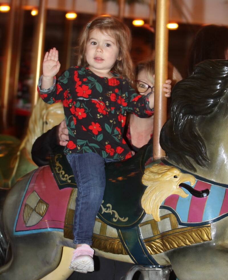 Ava Hanson waves at the camera during her ride on the  Carrousel at Shelby City Park's Carrousel Christmas Event. 