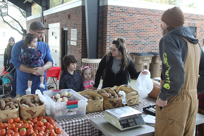 Noah Sisk of Lewis Farms in Fallston helps the Thompson family Dave, Isla, Jaxon, Evely and Ashley at the Foothills Farmers Market.