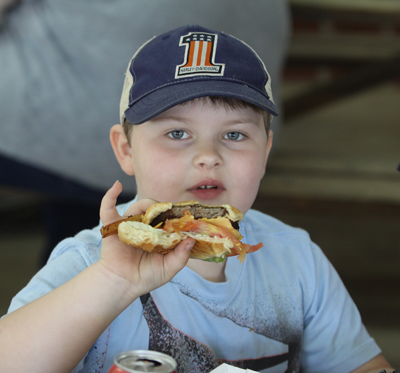 Braiden Henderson gets ready to take another bite of his burger at the Cruising for the Kids Cruise-In and Car Show in Boiling Springs.