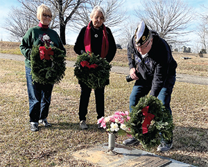 Legion District 23 Commander Jim Quinlan places a wreath on the grave of a female U.S. Marine who died at a young age.