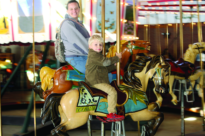 Suzanne Hobson and son Gunnar  riding on the horses at Shelby City Park  Carrousel 